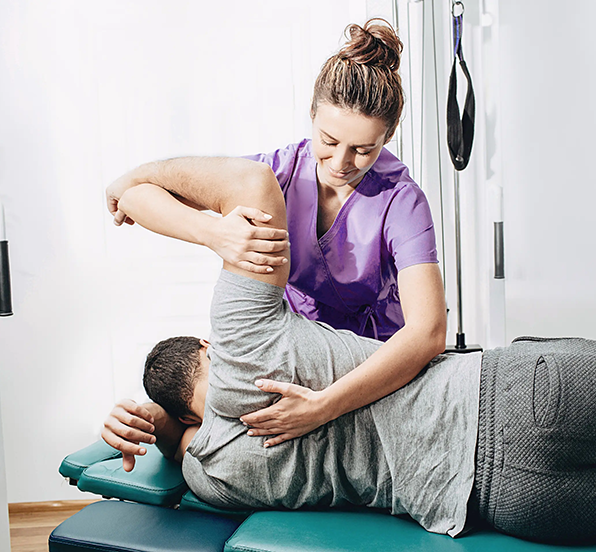 596x552_physical-therapist-assists-man-with-exercise-on-ta-2026-03-09-02-57-20-utc
